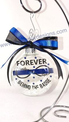 a clear ornament with a blue ribbon on it that says forever behind the badge