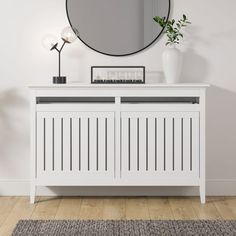 a white sideboard with a mirror on the wall and a plant next to it