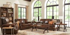 a living room filled with brown furniture and large windows in front of the window sill