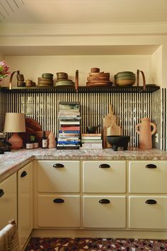 a kitchen with lots of pots and pans on the shelf above the stove top