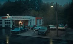 several cars parked in front of a building on a rainy day with the lights on