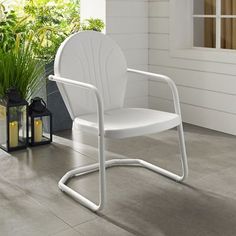 a white chair sitting on top of a cement floor next to a potted plant