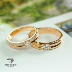 two gold wedding rings sitting on top of each other with diamond stones in the middle