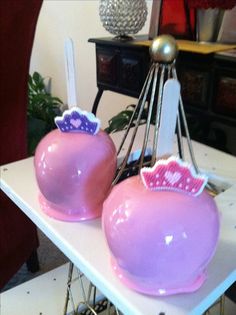 two pink vases with crowns on them sitting on a white table in front of a mirror