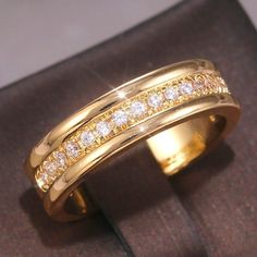 a yellow gold ring with white diamonds in it's center, sitting on top of a book