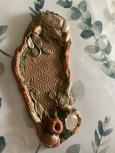 a cookie shaped like a fish on top of a tablecloth with leaves and flowers