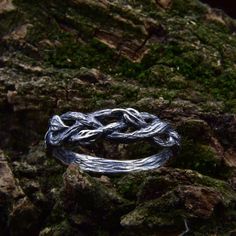 a silver ring sitting on top of a moss covered rock