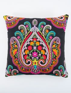 a black pillow with multicolored embroidered design on the front and back, sitting on a white surface