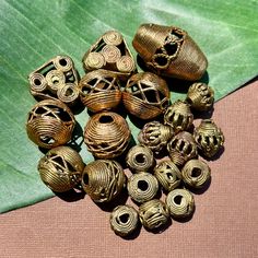 several pieces of gold colored metal sitting on top of a green leaf covered tablecloth