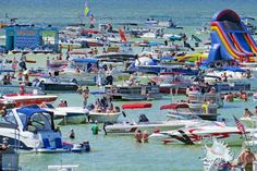 many boats and people in the water at a beach