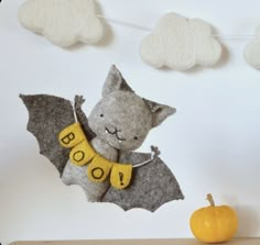 there is a stuffed bat hanging on the wall next to a pumpkin and some clouds