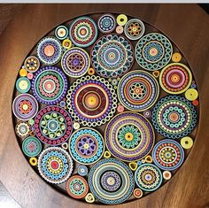 a wooden table topped with a colorful plate on top of it's side covered in circles