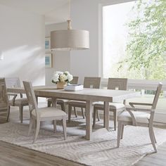 a dining room table and chairs in front of a window with an area rug on the floor