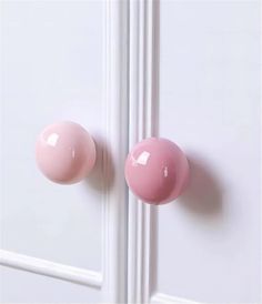 two pink door knobs on a white door