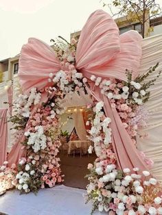 a pink and white wedding arch decorated with flowers