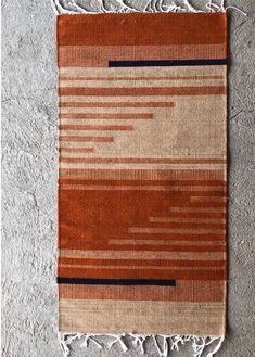 an orange and brown rug with fringes on the floor in front of a wall