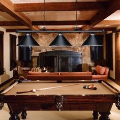 a pool table with two blue lamps hanging from it's ceiling in a living room