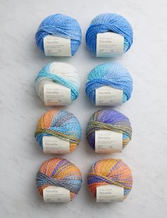 six skeins of multicolored yarn laid out on a white countertop