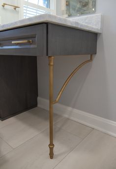 a marble top desk with gold legs in a room