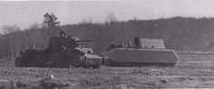 an army tank driving through a field next to a forest