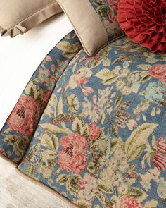 a close up of a pillow on a bed with floral designs and ruffles