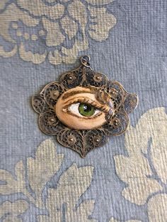 "Hand-painted Lover's Eye vintage silver filigree pendant. This piece of jewelry is a one of a kind, hand-painted by me on a vintage piece of jewelry selected also by me. It's painted with acrylic paint and varnished for protection and signed on the inside of the pin. The pendant is 1 3/4 wide x 1 1/2 inch wide. It comes with a silver plated chain - 18 inches long. \"The lover's eye is an 18th century variation on a portrait miniature of a secret love which typically displayed only the eye and e Handmade Antique Enamel Necklaces, Vintage Pendant Necklaces With Artistic Design, Vintage Pendant Necklace With Artistic Design, Vintage Hand Painted Round Pendant Necklace, Bohemian Hand Painted Jewelry For Art Collection, Vintage Hand-painted Pendant Necklace, Vintage Hand Painted Pendant Necklace, Vintage Collectible Jewelry With Artistic Design, Vintage Hand Painted Jewelry Gift