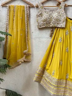 A three-piece mustard and beige mirror lehenga set from the Priti Sahni collection. This mustard georgette floral mirror embroidery butti lehenga with a heavy border of zari-pearl work detail is paired with a raw silk beige cutwork blouse with mirror, zardozi, resham work all over it. This outfit is completed with a mustard tulle net dupatta with scallop edging with highlights. Transitional Chanderi Lehenga With Gota Work, Yellow Sets With Gota Work For Transitional Season, Yellow Sets With Gota Work For Seasonal Transition, Transitional Yellow Sets With Gota Work, Festive Yellow Pre-draped Saree With Mirror Work, Transitional Gold Sharara With Dori Work, Yellow Cutdana Sharara For Reception, Transitional Yellow Sharara With Zari Work, Yellow Chanderi Sets For Reception