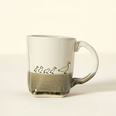 a coffee cup with three birds on it sitting on a table in front of a white background