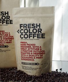 two bags of fresh color coffee sitting on top of some coffee beans