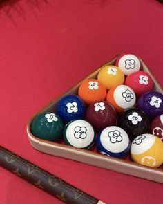 pool balls in a triangle shaped container on a pink surface