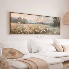 a living room with a large painting on the wall and white couches in front of it