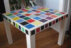 a multicolored table sitting on top of a hard wood floor next to a potted plant