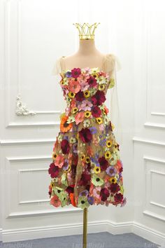 a dress made out of flowers on a mannequin with a crown in the background