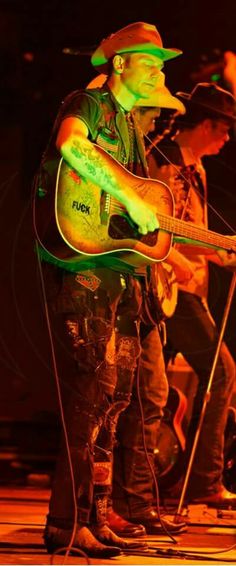 a man holding a guitar while standing on top of a stage