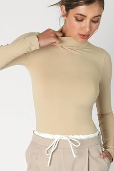 Indulge in timeless elegance with our Pearl Long Sleeve Mock Neck Top. Crafted from a luxurious blend of 92% Nylon and 8% Spandex, this seamless top is designed to provide a form-fitting look for effortless layering. Made in the USA, it serves as the perfect base layer for any ensemble, offering a cozy neckline and a sophisticated silhouette. Elevate your style with this essential piece from our premium collection. Elegant High Stretch Tops With Thumbholes, High Neck Tops With Thumbholes In Elastane, High Neck Tops With Thumbholes, Stretch Long Sleeve Tops With Seamless Collar, High Neck Seamless Stretch Top, High Neck Seamless High Stretch Top, High Stretch Seamless High Neck Top, Elastane Tops With Thumbholes, High Stretch Elastane Tops With Seamless Construction