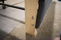 a close up of a wooden door handle on a bed frame with a person's feet in the background