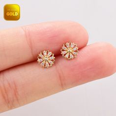 a pair of gold colored earrings with small flowers on the front and back of each ear