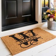 a welcome mat with the word wilson on it next to a potted plant and door