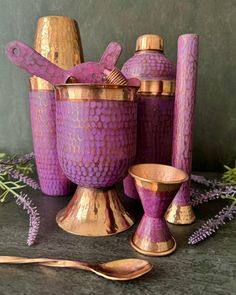 purple vases and spoons are sitting on a table