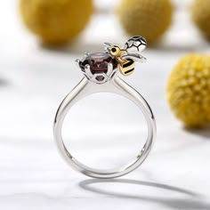 This bee ring is inspired by the nature. Bees symbolize hard working, loyalty and team spirit. Said to bring the wearer light, joy and peace, this bee style symbolizes sweet love. Certain to win her heart, this ring is finished with a bright polished shine. Crafted in sterling silver, this ring in Hug Me® collection features a shimmering round cut stone hugged by a little flying bee, which is designed to be so lovely and super-active. You will find more adorable and creative designs in our Hug Me® collection.Carat Weight: 2.5 ctStone Size: 7 mmStone Type: Jeulia® StoneNumber of Stones: 1 Stone Color: ChocolateStone Shape: RoundWeight: 3.61 gMaterial: 925 SilverPlating Color: Silver, Yellow Gold Flying Bee, Honey Jewelry, Bee Ring, Joy And Peace, Fancy Jewellery Designs, Bee Inspired, Soulmate Quotes, Bee Jewelry, Jewellery Brand