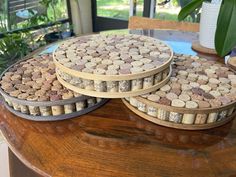 three wooden trays filled with wine corks sitting on top of a table next to a potted plant