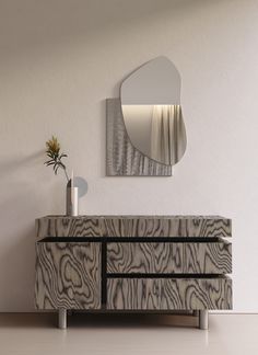 a white and black dresser with a mirror on the wall next to a plant in a vase