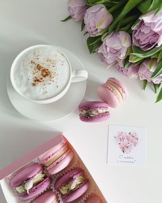 pink macaroons are sitting next to a cup of coffee and some tulips