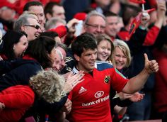 a man in a red jersey is surrounded by people and giving the thumbs up sign