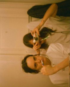 two women brushing their teeth in front of a mirror