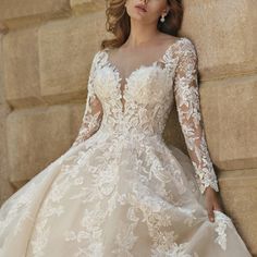 a woman in a wedding dress leaning against a stone wall