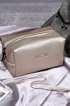 a metallic bag sitting on top of a white sheet next to a cell phone and purse