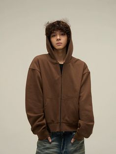 a young man wearing a brown hoodie and jeans