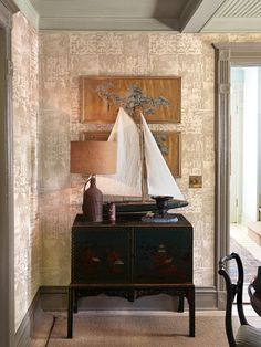 a sailboat is sitting on top of a cabinet in a room with wallpaper