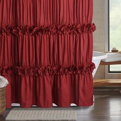 a red shower curtain with ruffles on it in a bathroom next to a bathtub